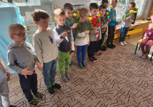 Chłopcy stoją w rzędzie z upominkami dla dziewczynek