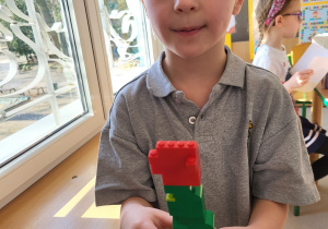 Chłopiec prezentuje ułożony przez siebie kwiatek z klocków