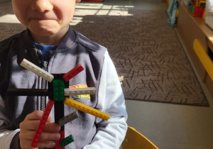 Chłopiec prezentuje ułożony przez siebie kwiatek z klocków