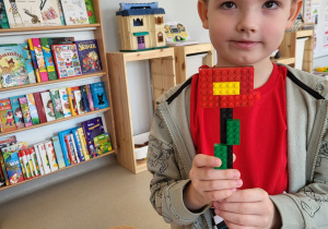 Chłopiec prezentuje ułożony przez siebie kwiatek z klocków