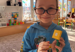 Chłopiec prezentuje ułożony przez siebie kwiatek z klocków