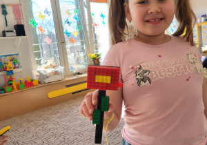 Dziewczynka prezentuje otrzymany kwiatek z klocków