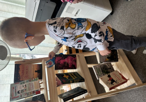 Chłopiec ogląda książki na półce