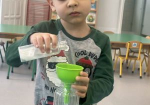 Chłopiec wlewa farbę do butelki z wodą