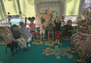 Dziewczynki siedzą w kole z kwiatami