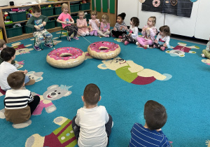Dzieci zwijają sznurek na rurkę, przyciągając do siebie balony w kształcie donutów