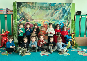 Dzieci pozują do wspólnego zdjęcia z figurkami dinozaurów