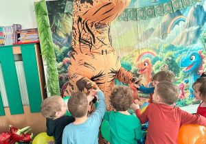 Dzieci witają się z wysoką dmuchaną postacią dinozaura