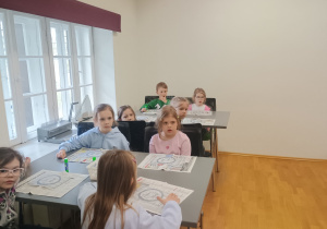 Dzieci wyklejają witraż bibułą