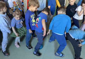 Dzieci stoją w rzędach i przekazują sobie piłki
