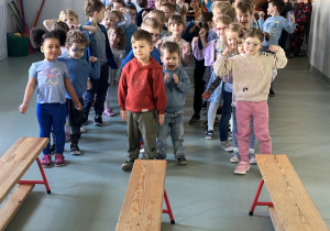 Dzieci stoją w rzędach przed ławkami