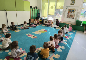 Prowadząca pokazuje dzieciom ilustracje z książki omawiając je