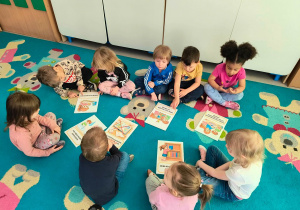 Dzieci wspólnie oglądają ilustracje i rozmawiają o tym jak dbać o książki